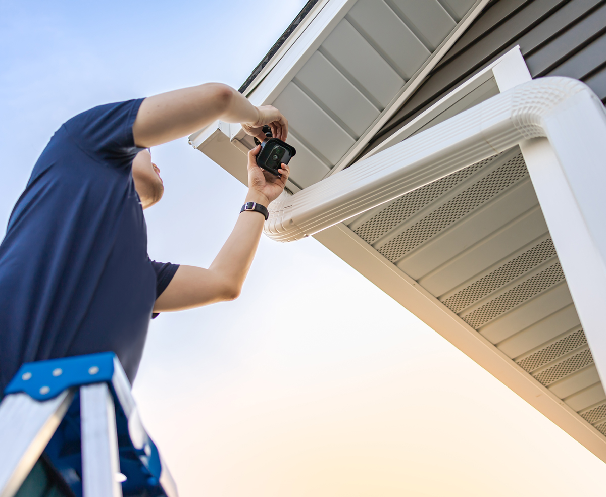 Technician on ladder installing and adjusting wireless security